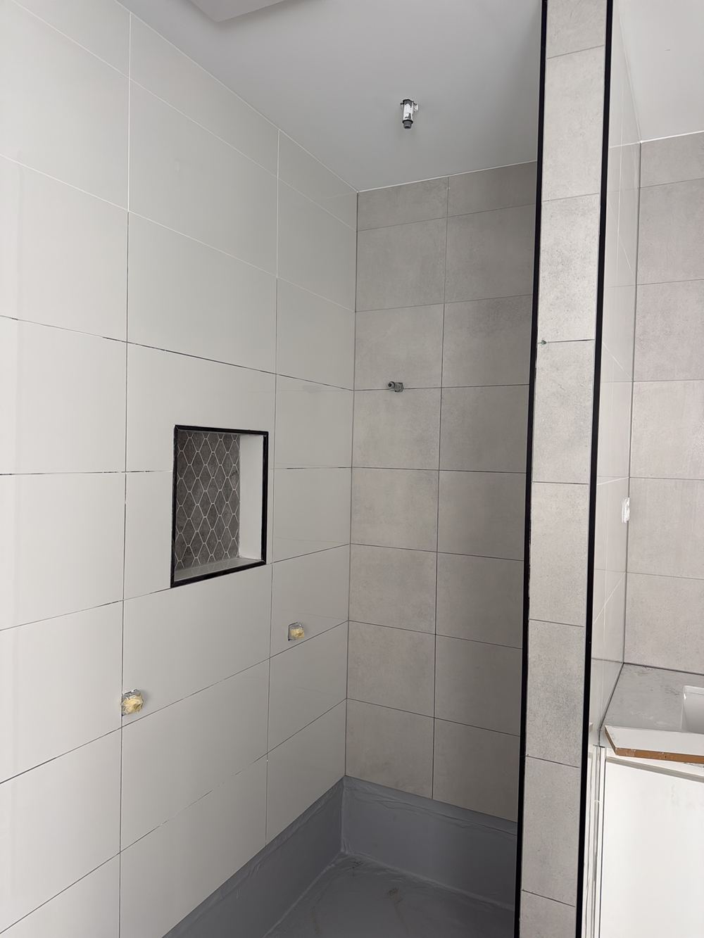 Hollow-sounding wall tiles that appear to be spot fixed, found during a defect investigation in Berwick