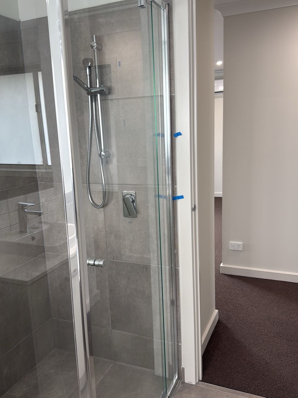 Shower within 200mm of the bathroom exit with no vertical water stop, found during a pre-handover inspection in Berwick